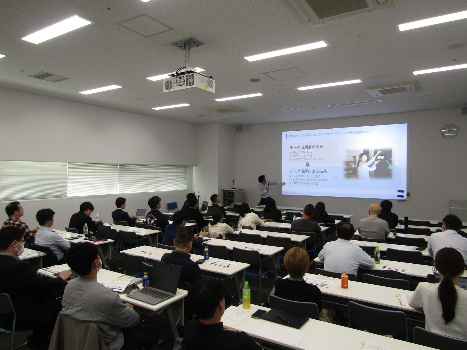 多くの参加者が集まった会場で、地方カフェのデータ活用事例を解説する講師